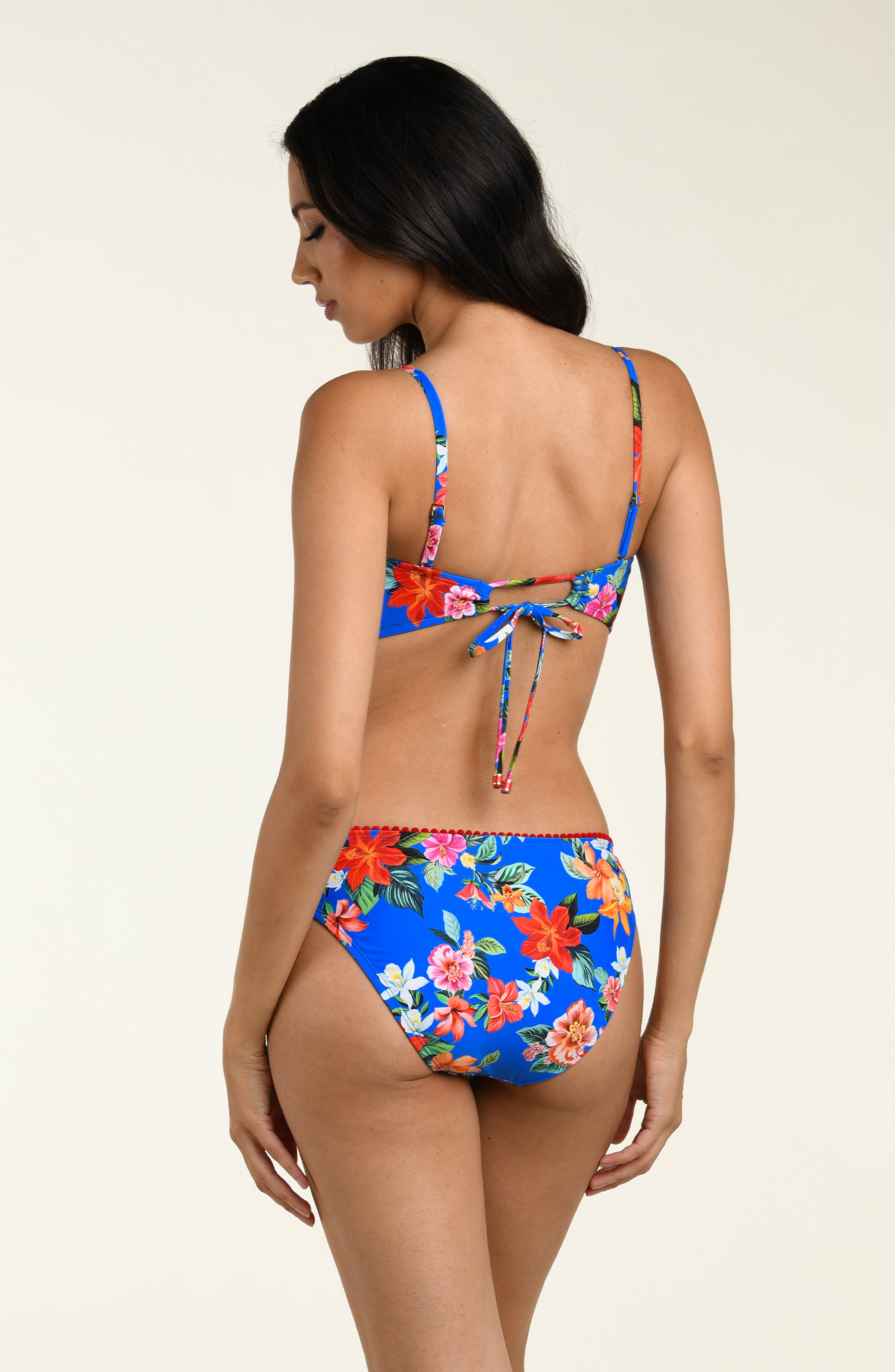 Woman wearing a multicolored bikini top and matching bottom against a white background. 