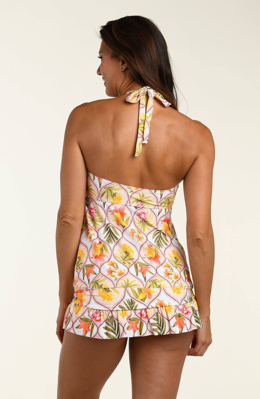 Woman wearing a floral halter tankini top and a matching swim skirt with a white background