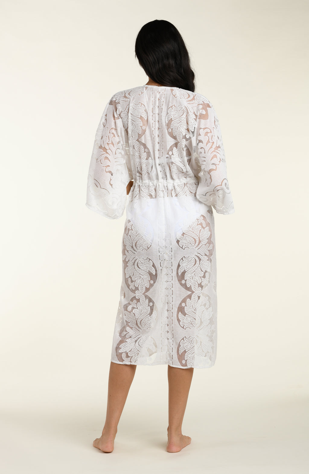Woman wearing a white lace kimono on a plain background