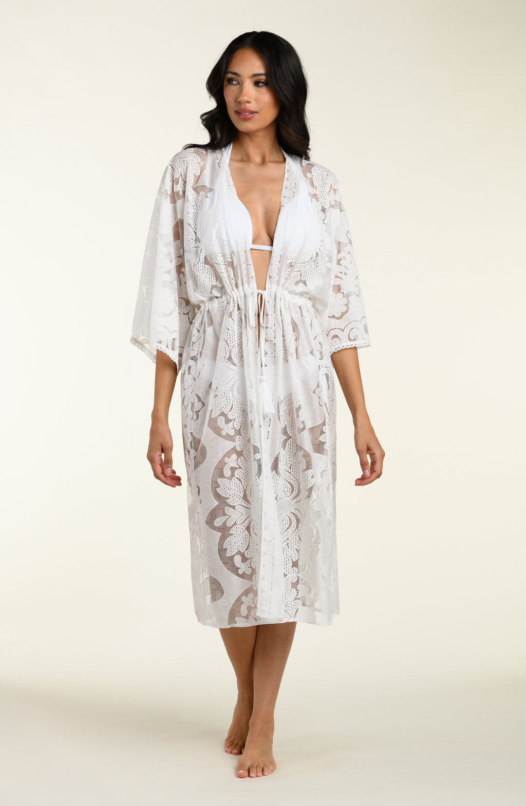Woman wearing a white lace kimono on a plain background