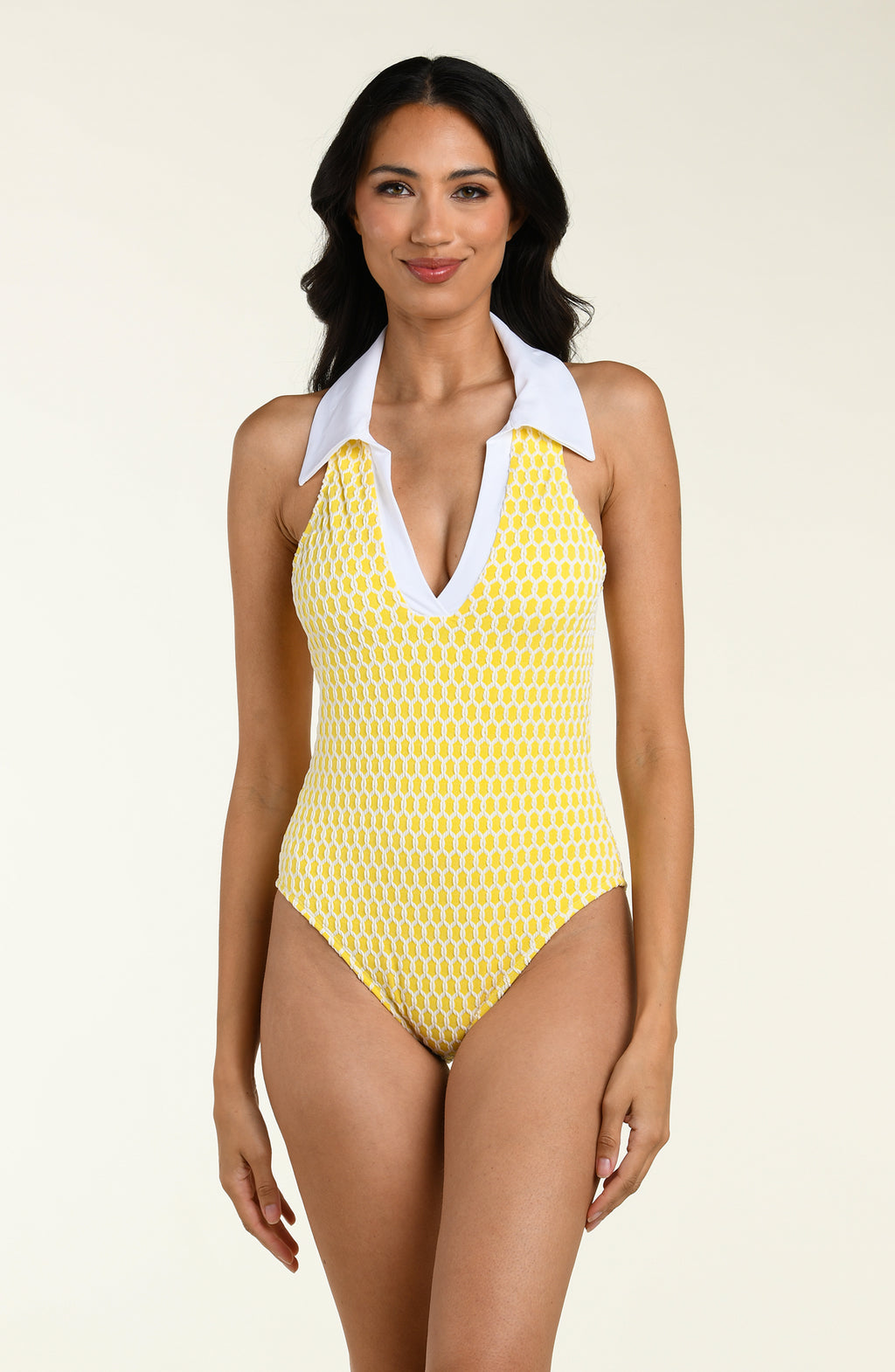 Woman wearing a yellow patterned one-piece swimsuit with a white collar on a beige background