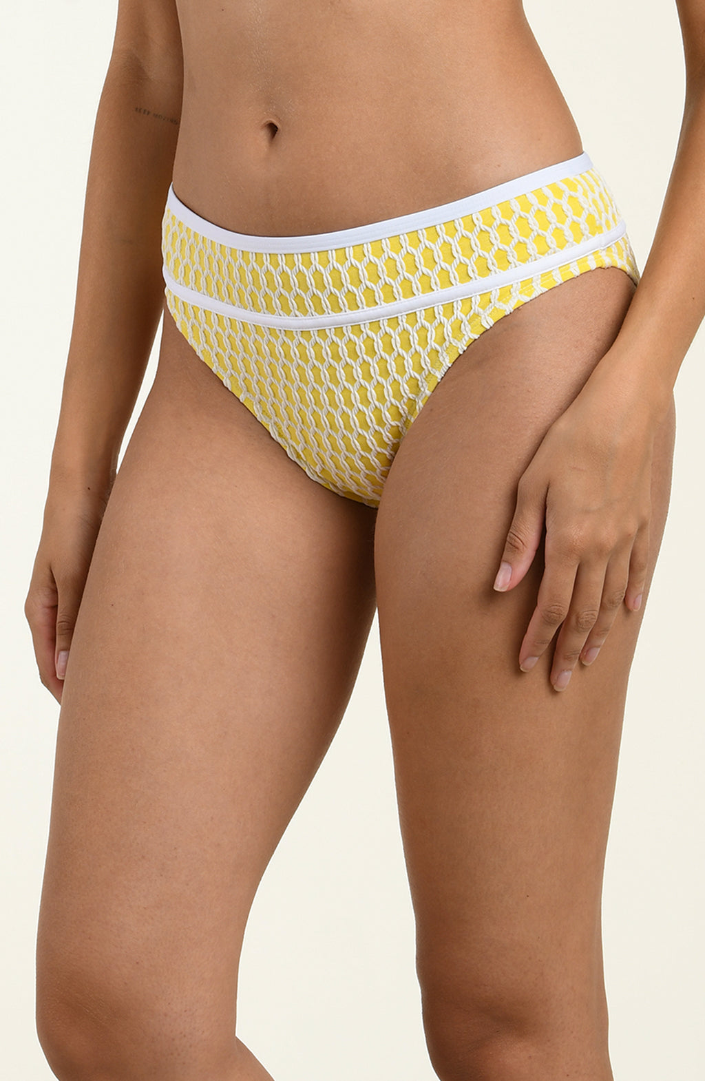 Yellow patterned bikini bottom worn by a person on a beige background