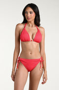 Woman wearing a guava colored bikini top and matching bottom against a white background. 