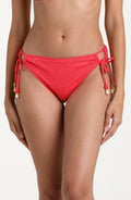 Woman wearing a guava colored bikini bottom against a white background. 