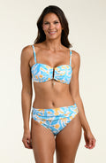 Woman wearing a blue and yellow patterned bikini top and matching bikini bottom on a beige background