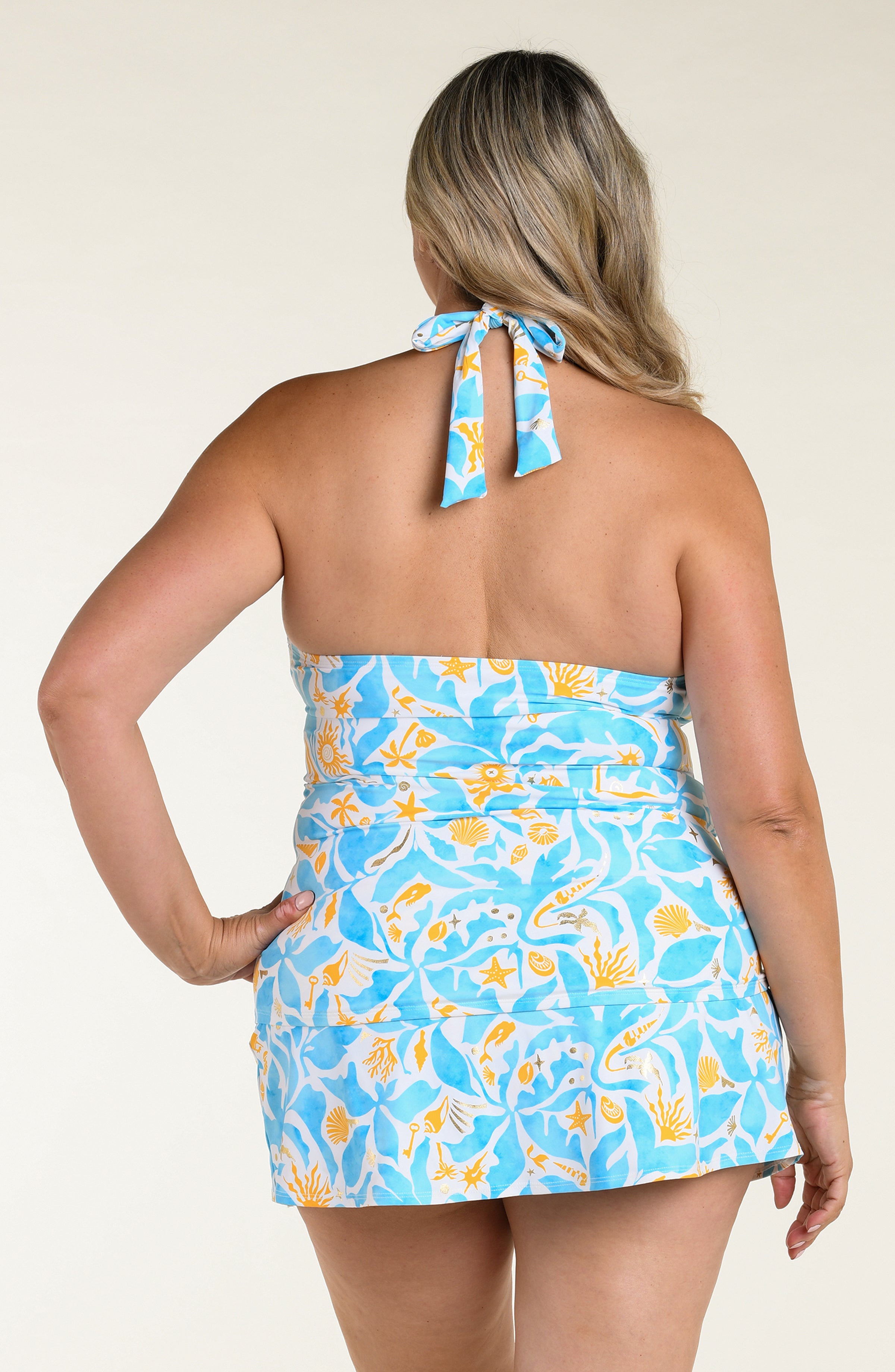 Woman wearing a multicolored tankini top and matching swim skirt against a white background. 