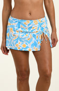 Woman wearing a multicolored blue and white swim skirt against a white background. 