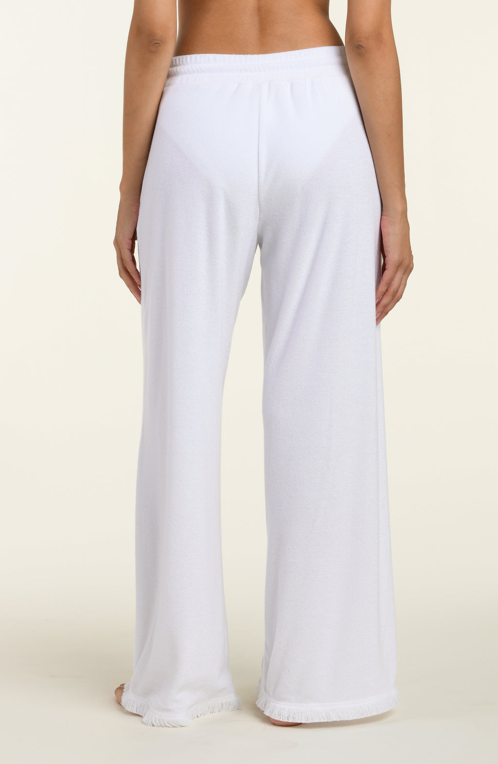 White cover up beach pants worn by a person on a beige background