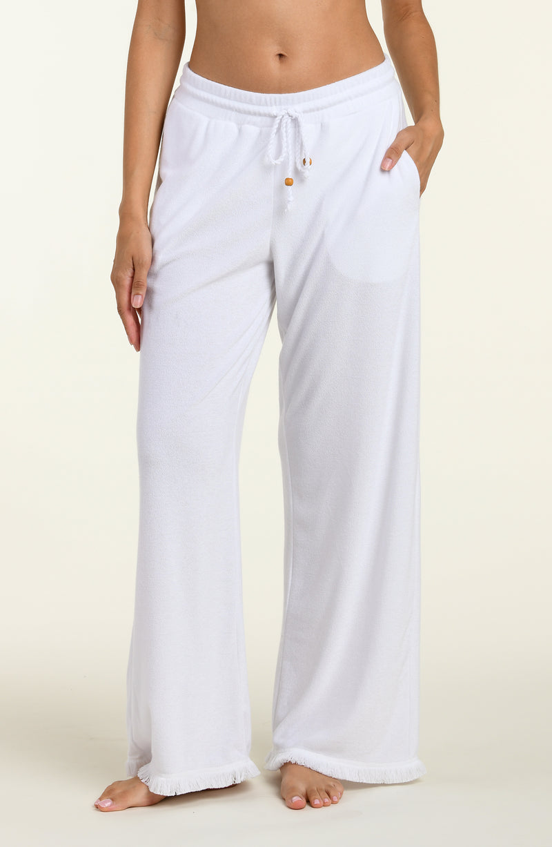 White cover up beach pants worn by a person on a beige background