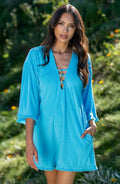 Woman wearing a blue tunic cover up with a blurred green background