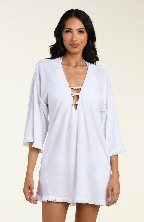 Woman wearing a white cover-up tunic  with lace-up front on a beige background