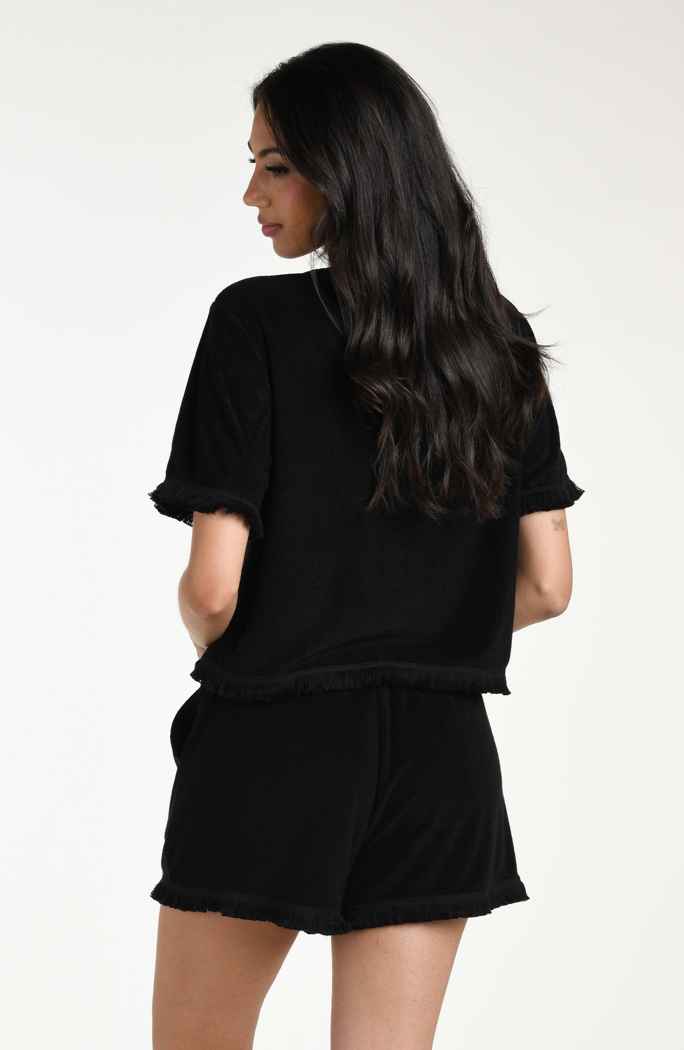 Woman wearing a black short sleeve top and matching beach shorts against a white background