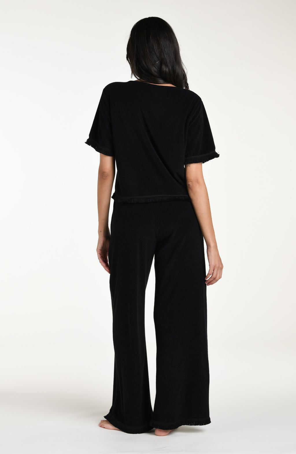 Woman wearing a black short sleeve top and matching beach pants against a white background