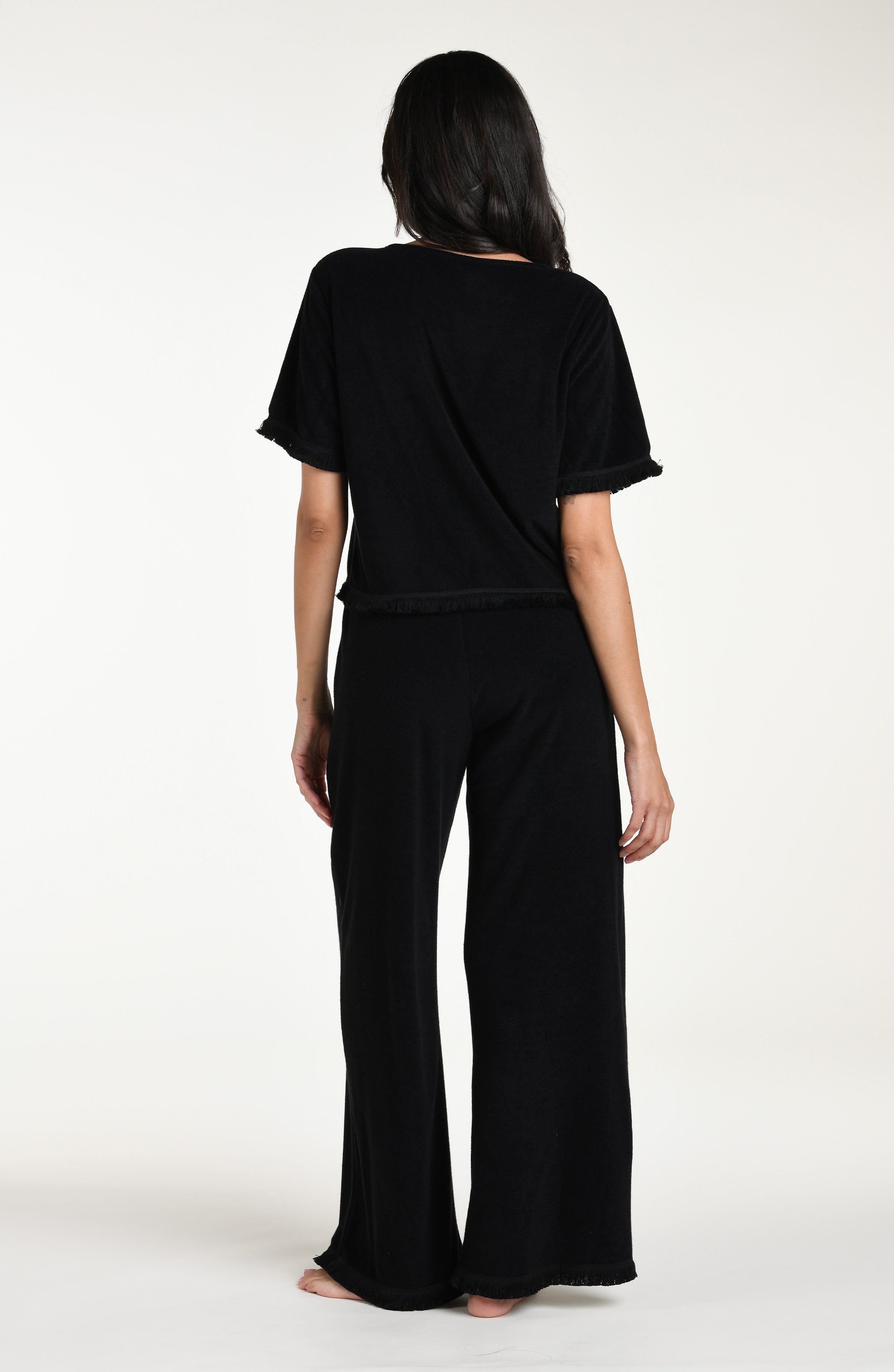 Woman wearing a black short sleeve top and matching beach pants against a white background