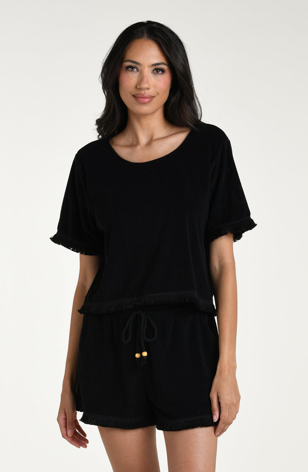 Woman wearing a black short sleeve top and matching beach shorts against a white background
