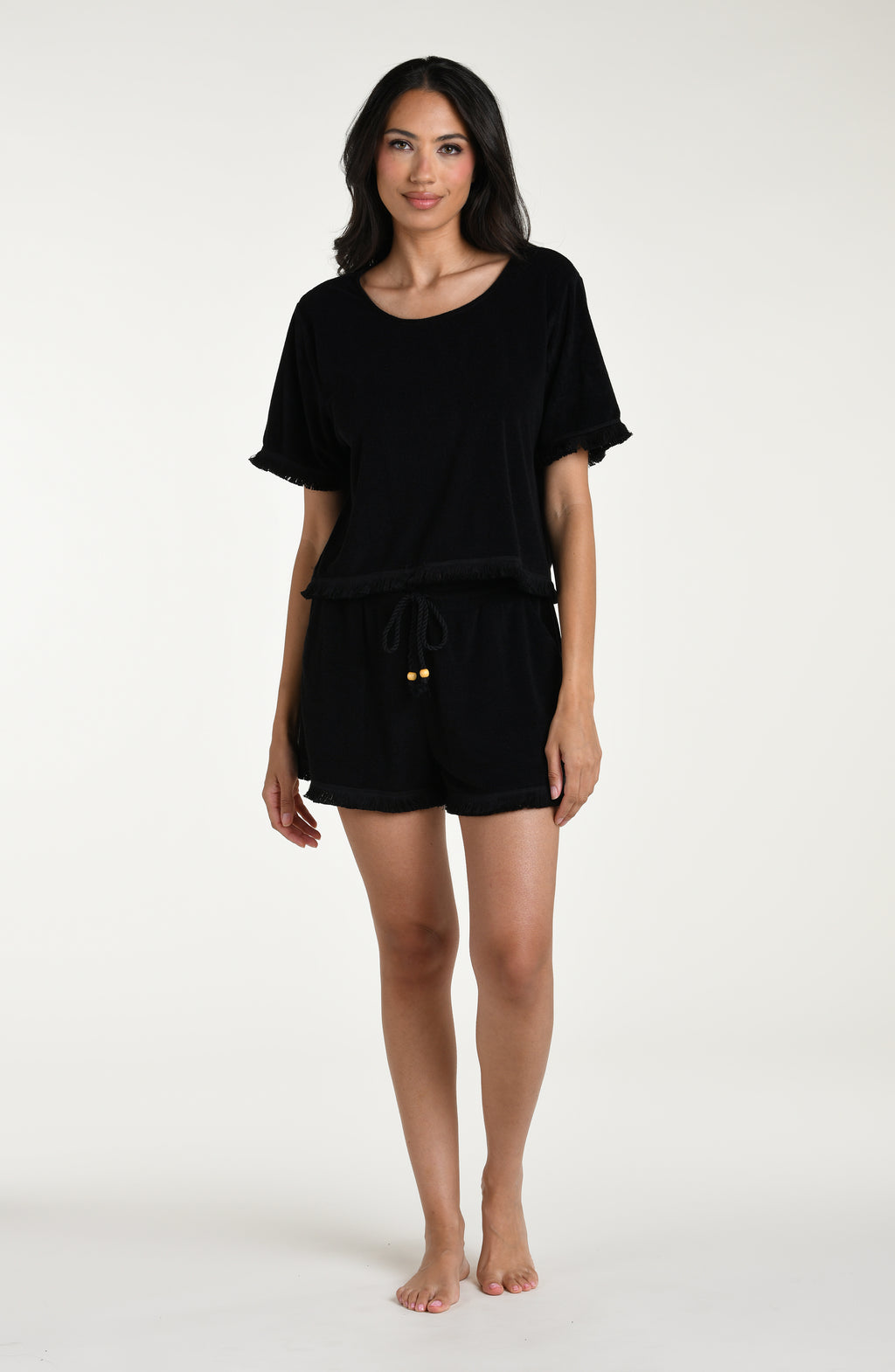 Woman wearing a black short sleeve top and matching beach shorts against a white background