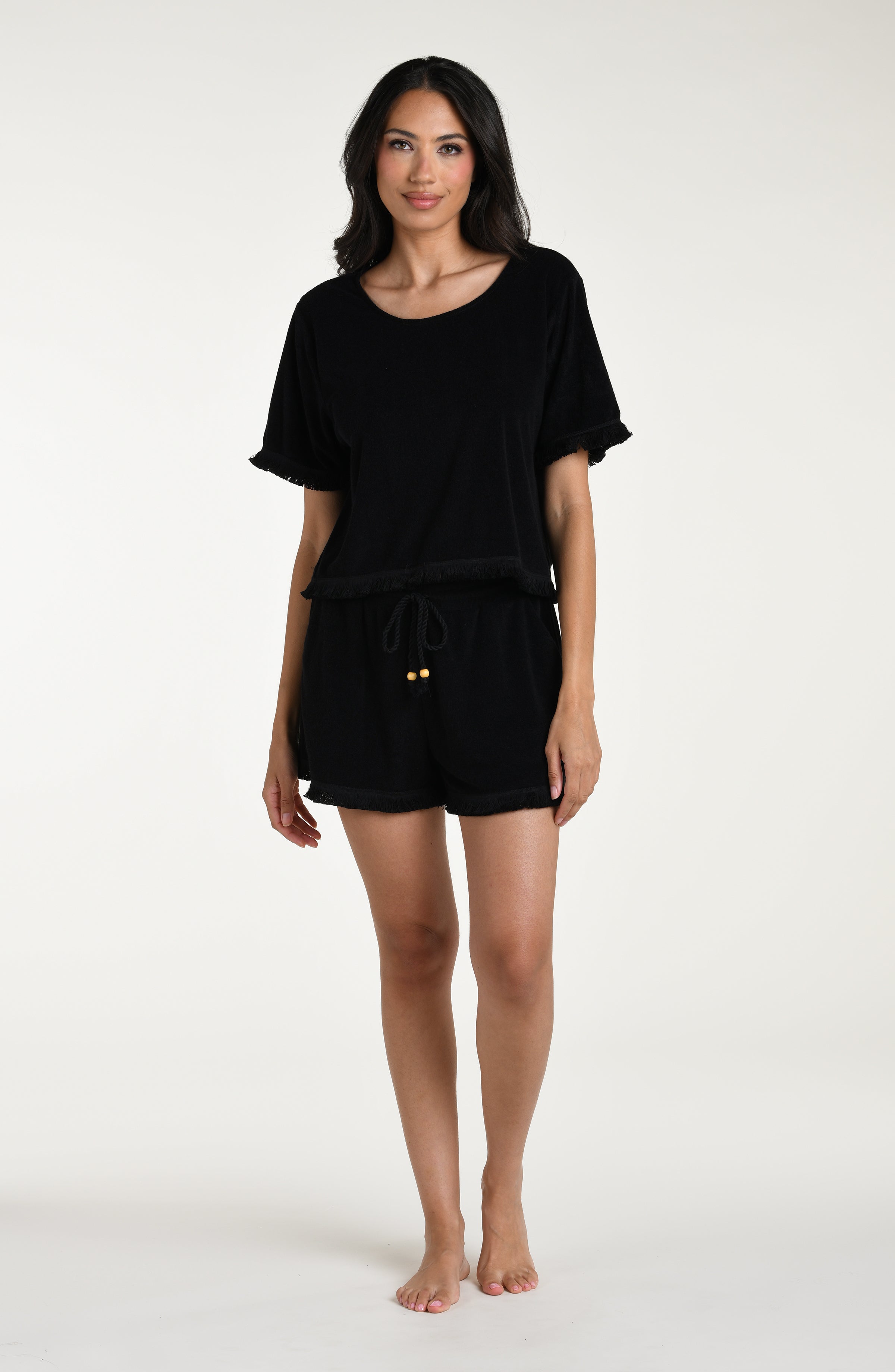 Woman wearing a black short sleeve top and matching beach shorts against a white background