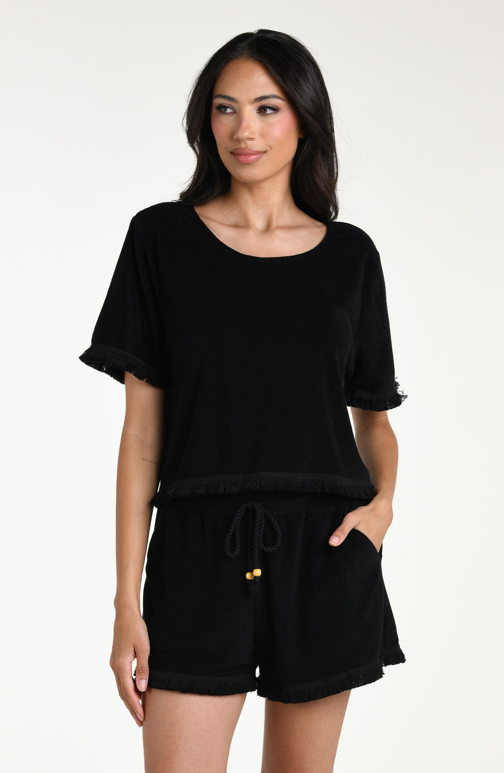 Woman wearing a black short sleeve top and matching beach shorts against a white background