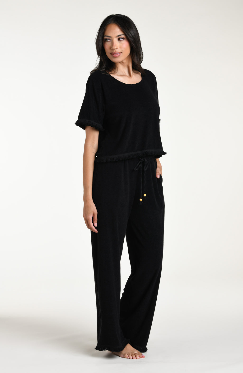Woman wearing a black short sleeve top and matching beach pants against a white background