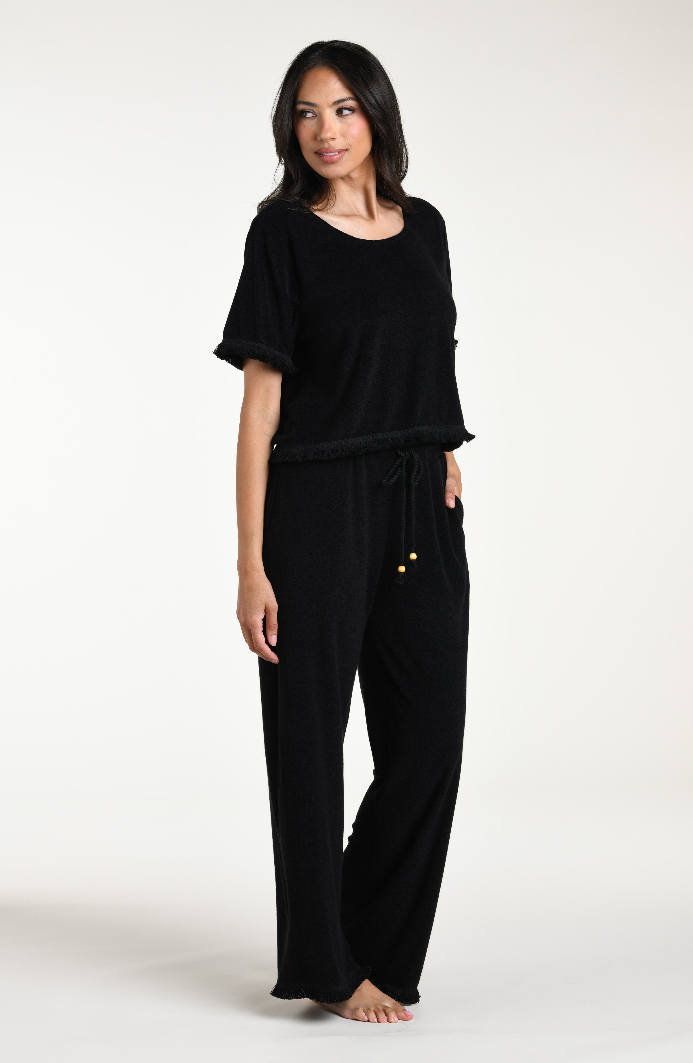 Woman wearing a black short sleeve top and matching beach pants against a white background