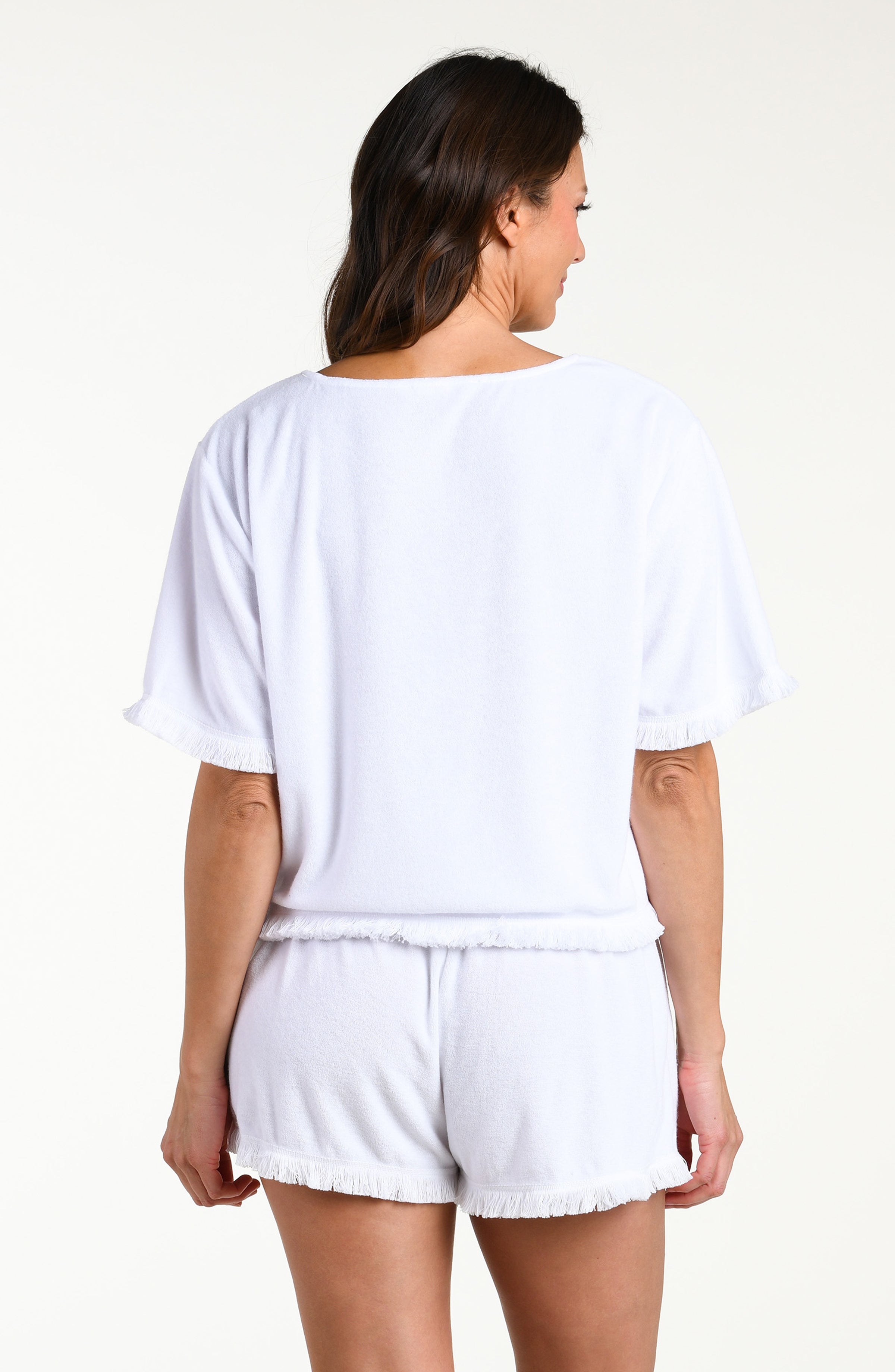 Woman wearing a white short sleeve top and matching shorts against a white background