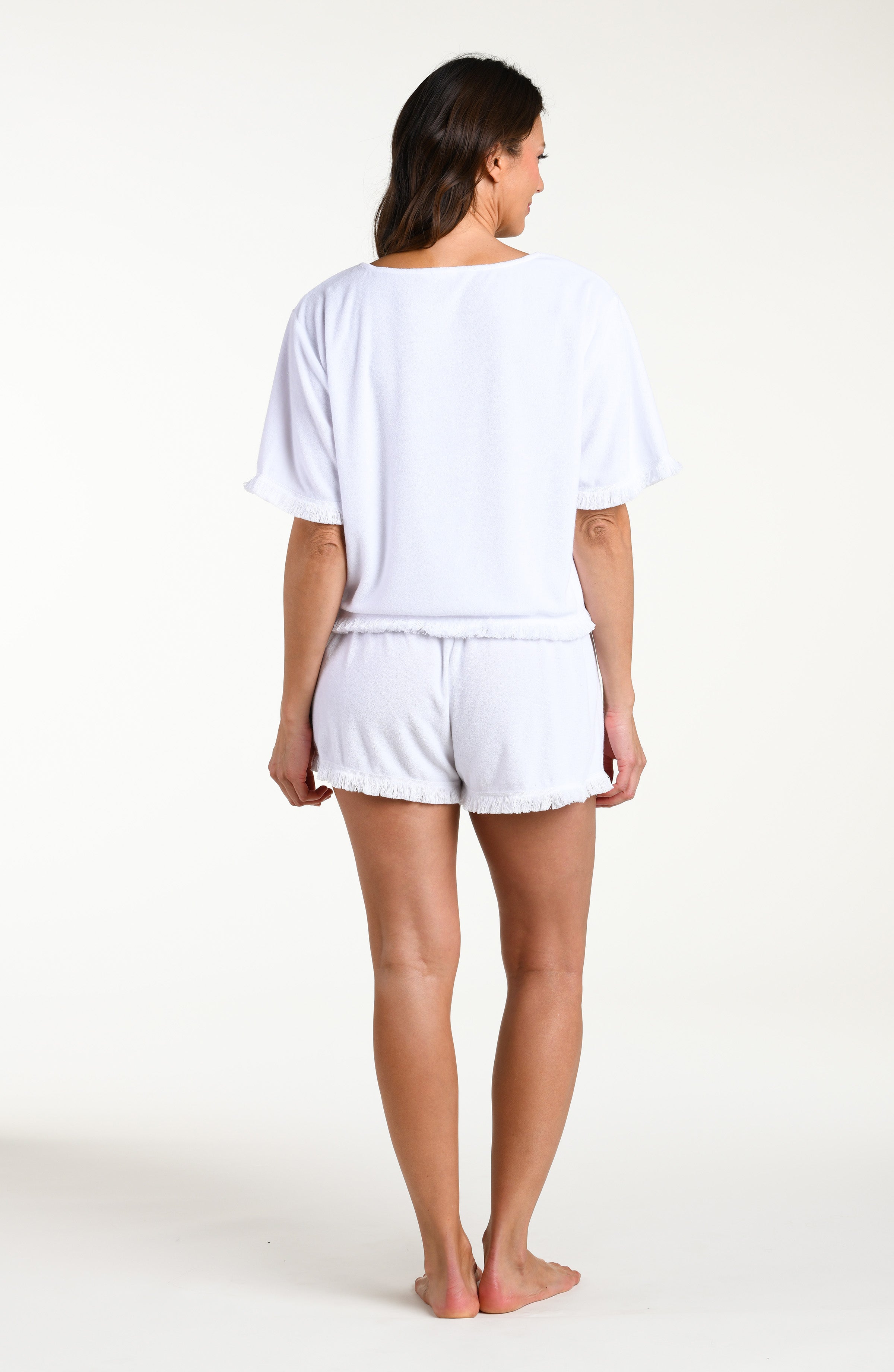 Woman wearing a white short sleeve top and matching shorts against a white background