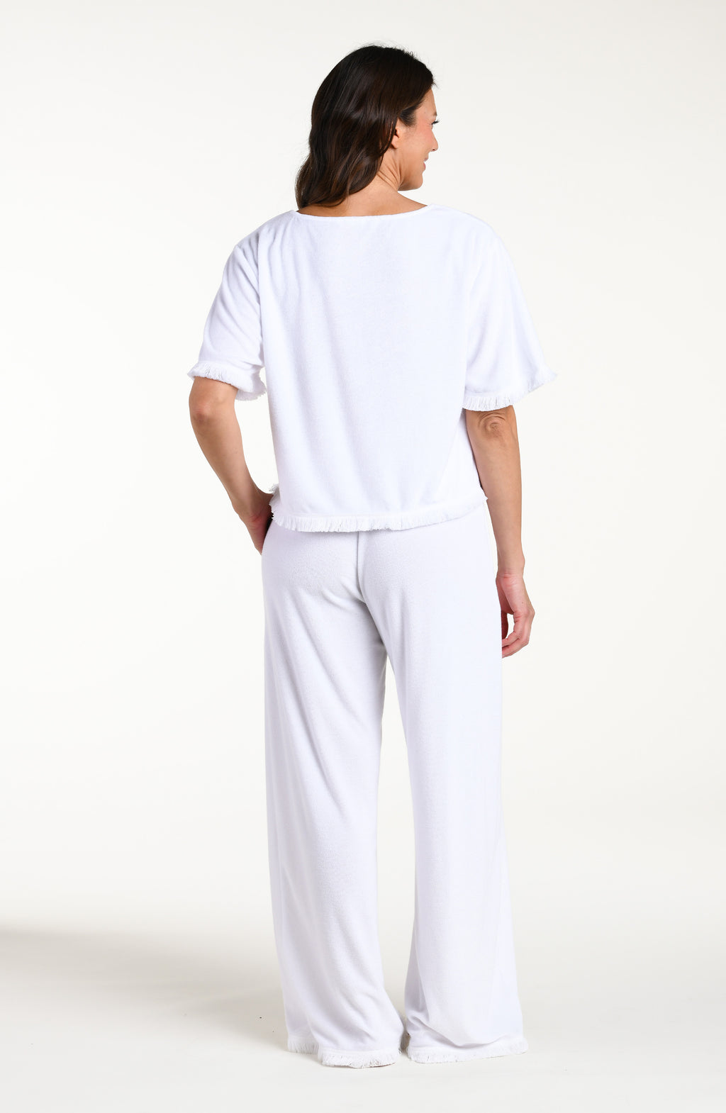 Woman wearing a white short sleeve top and matching beach pants against a white background