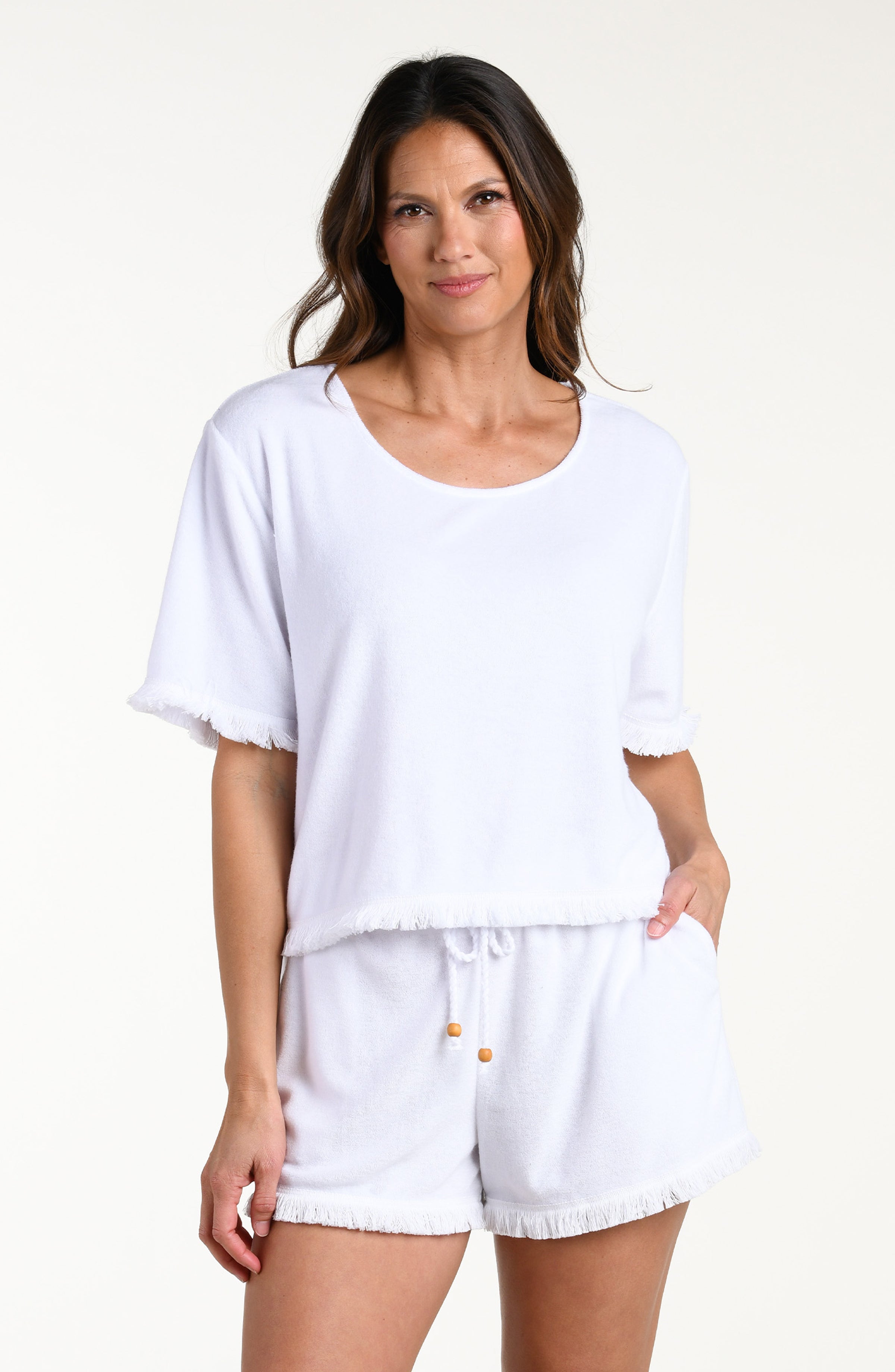 Woman wearing a white short sleeve top and matching shorts against a white background
