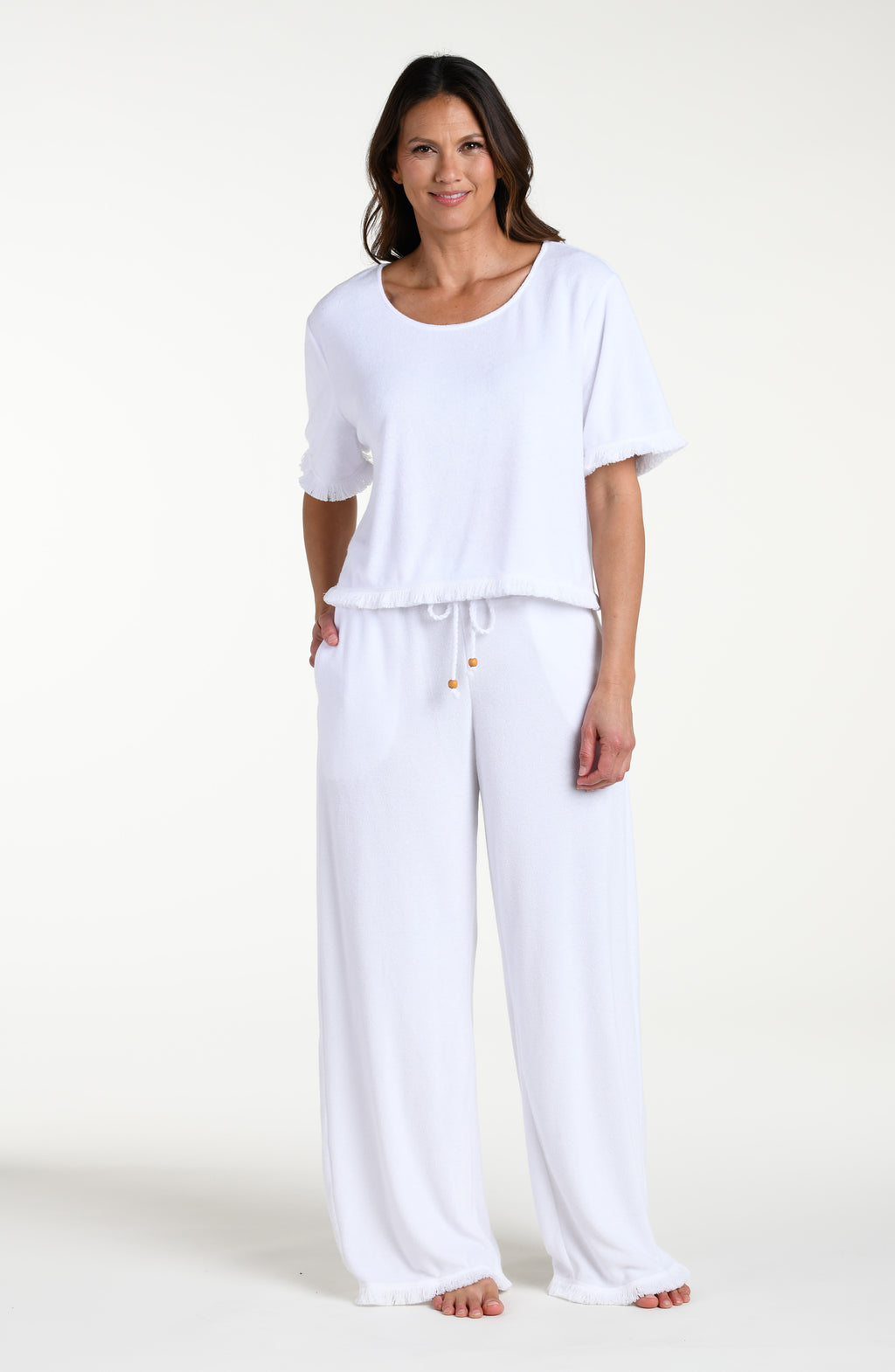 Woman wearing a white short sleeve top and matching beach pants against a white background