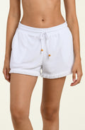 White shorts with drawstring and buttons worn by a person on a beige background