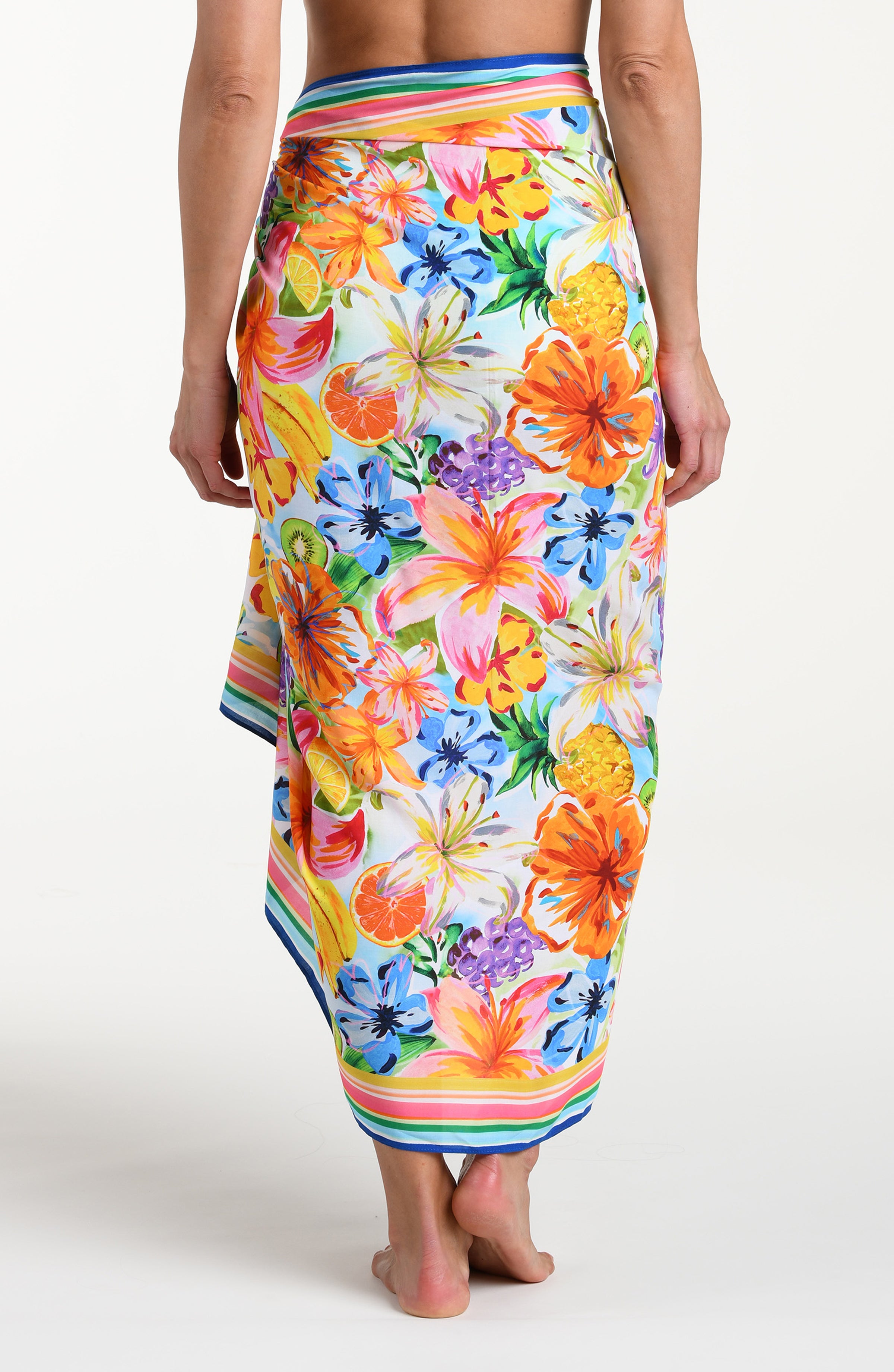 Woman wearing a colorful tropical pareo wrap against a white background.