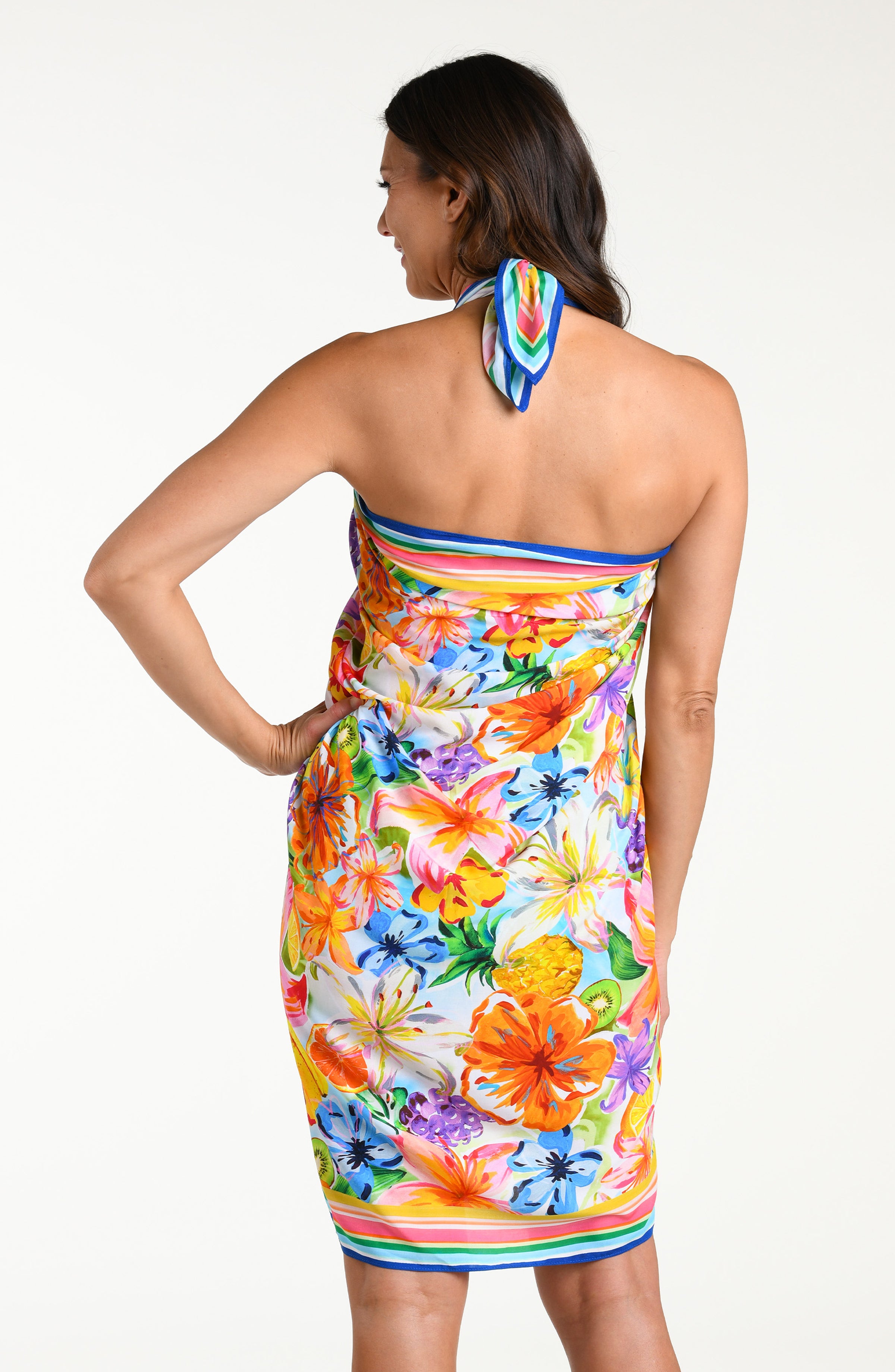 Woman wearing a colorful tropical pareo wrap against a white background.