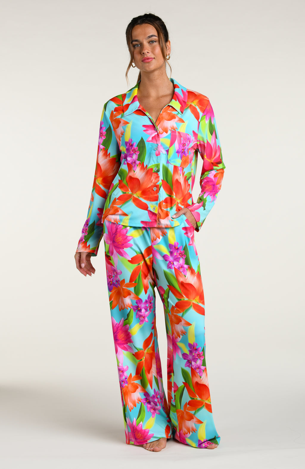 Woman wearing a colorful floral pajama pant set against a white background