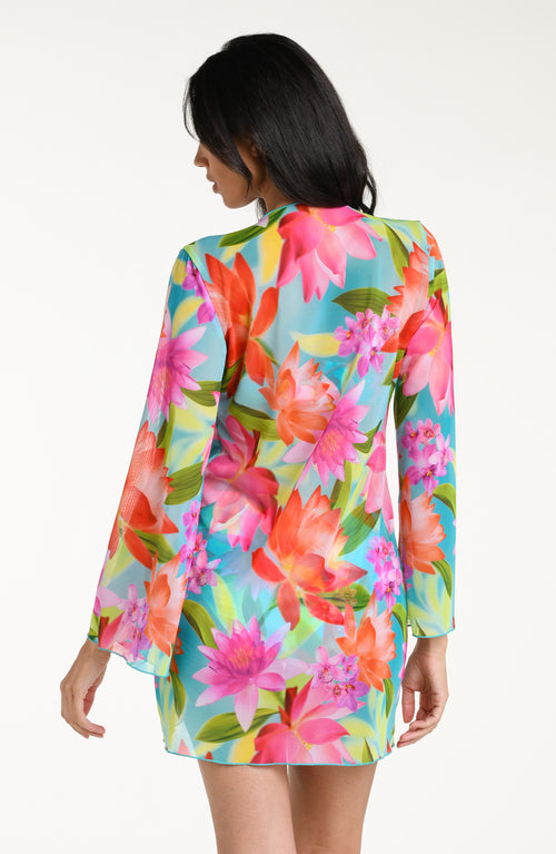 Woman wearing a bright floral kimono cover up with a matching bikini underneath, against a white background.