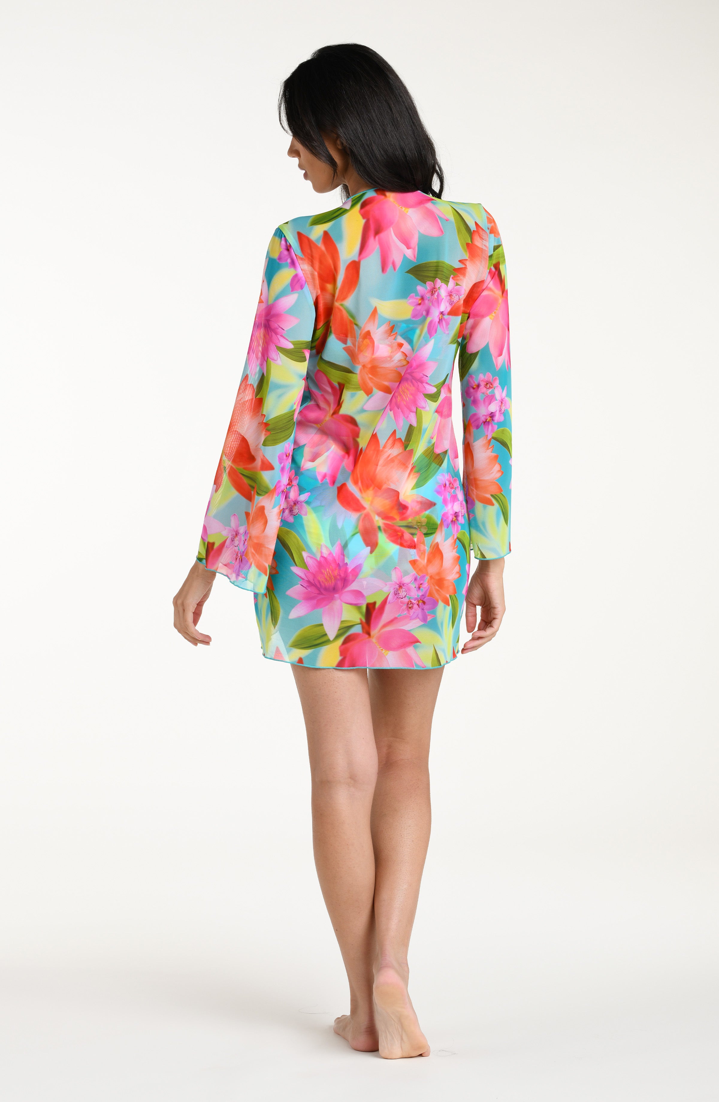 Woman wearing a bright floral kimono cover up with a matching bikini underneath, against a white background.