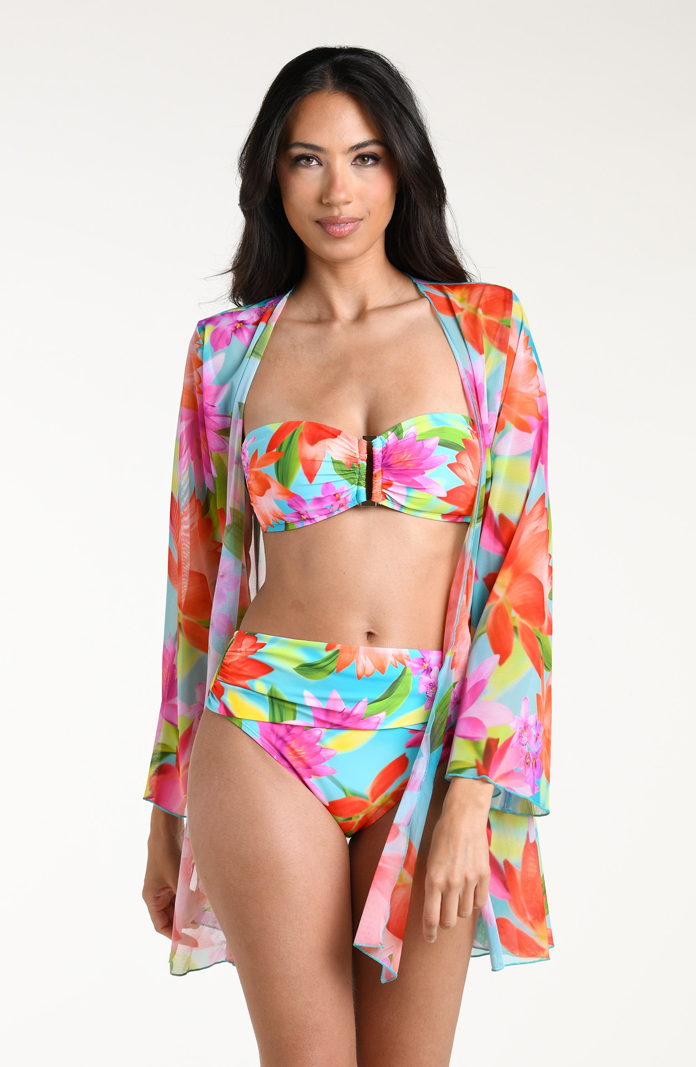 Woman wearing a bright floral kimono cover up with a matching bikini underneath, against a white background.