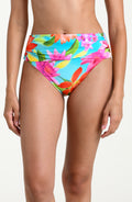 Woman wearing a bright floral bikini bottom against a white background