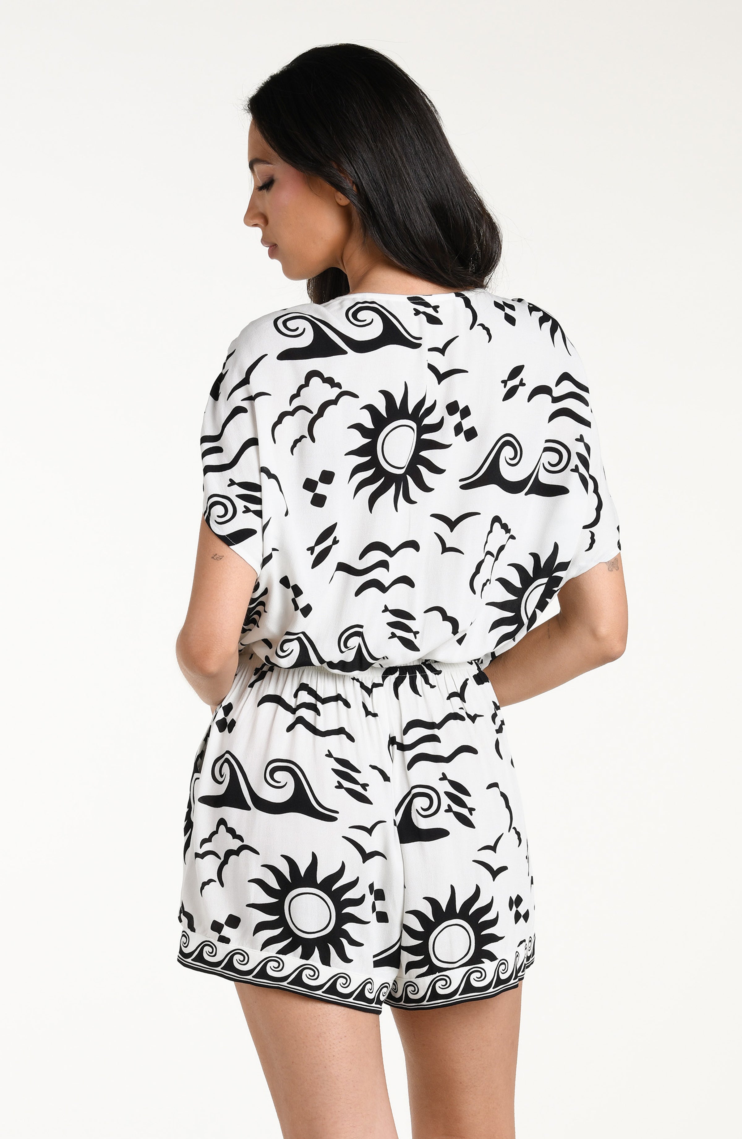 Woman wearing a black and white patterned romper against a white background