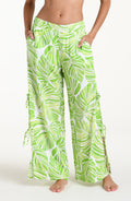 Woman wearing  green and white leaf-patterned beach pants against a white background