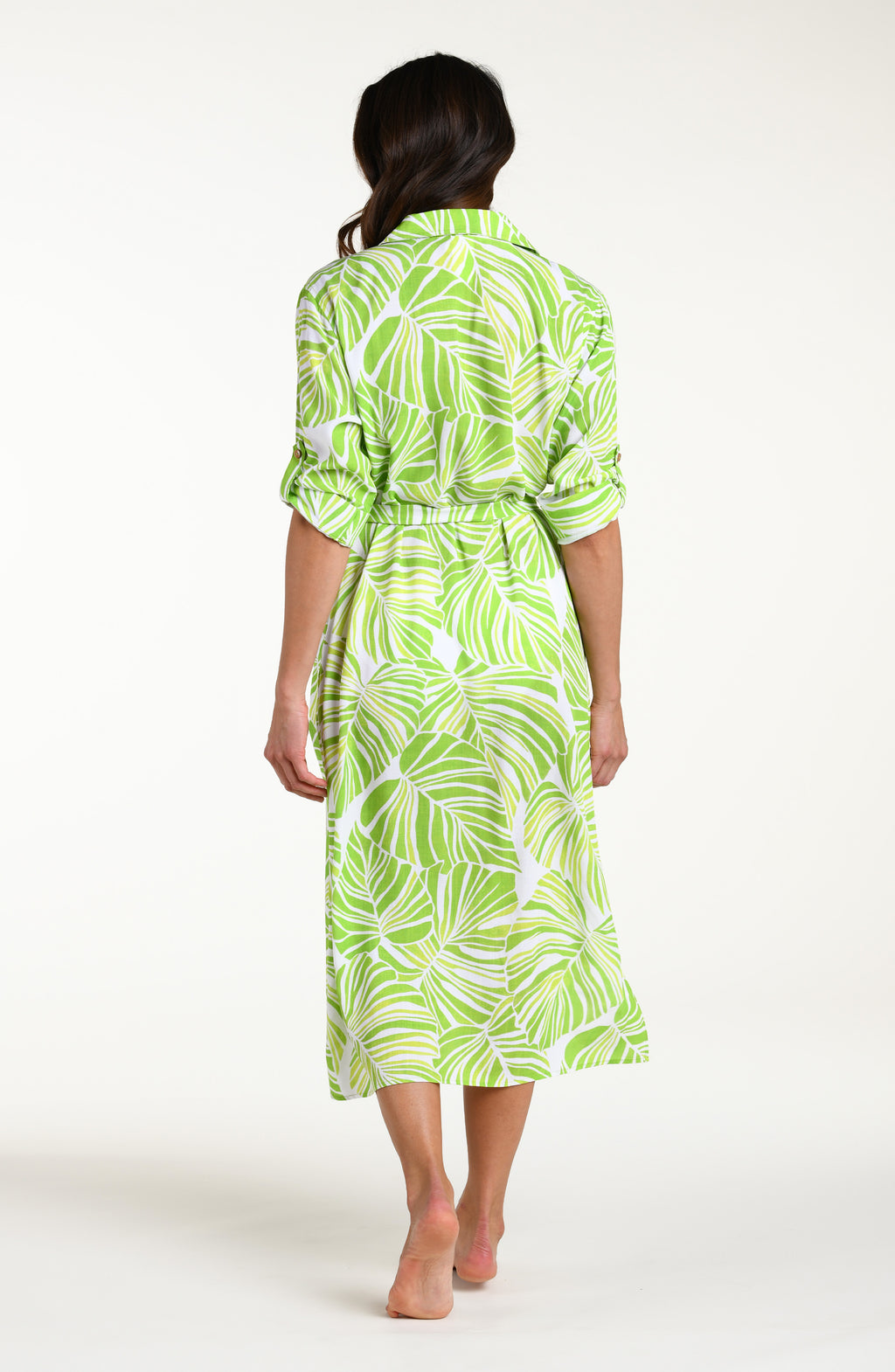 Woman is wearing a green and white leaf-patterned midi dress with a white bikini underneath, against a white background