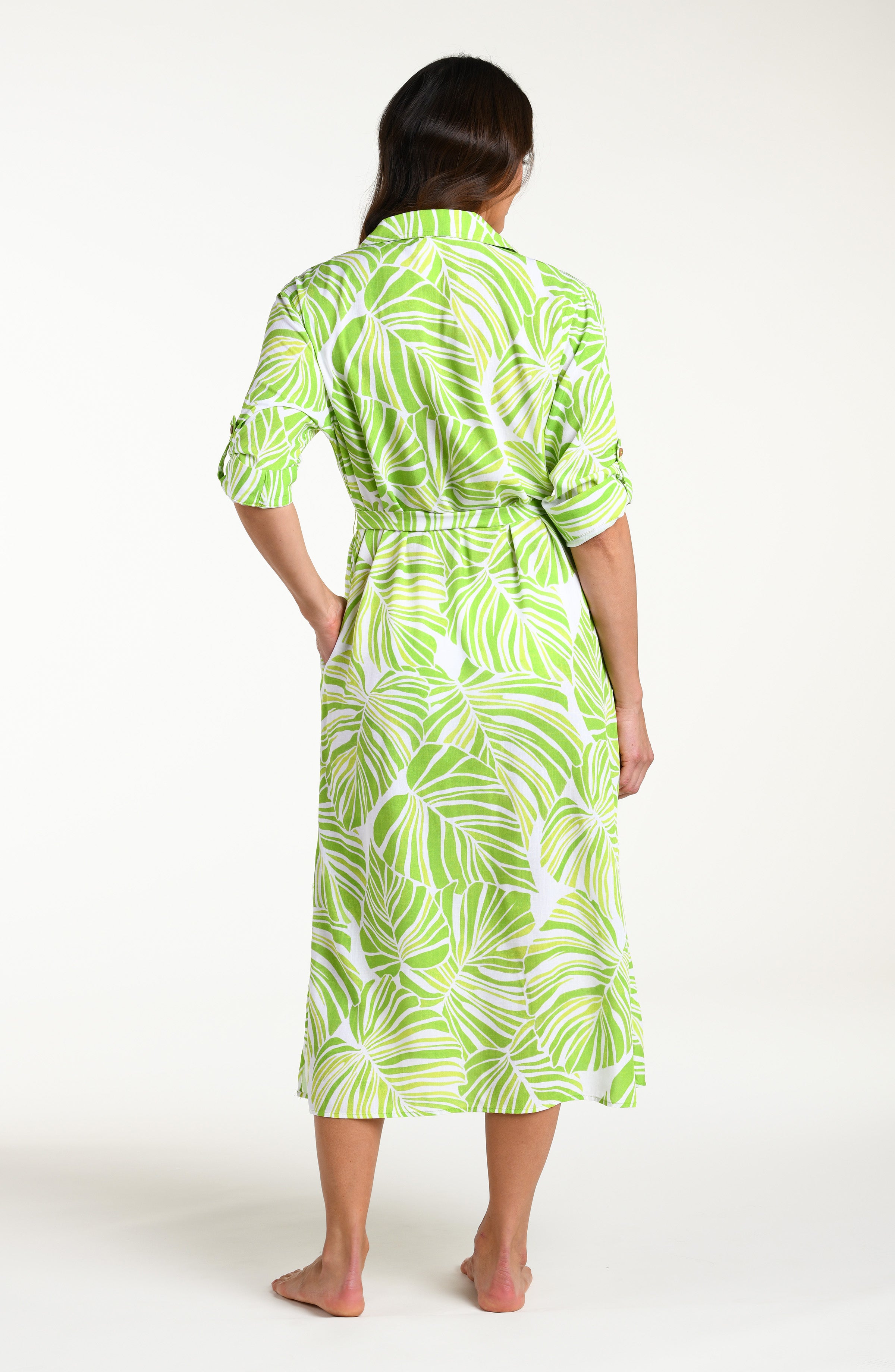Woman is wearing a green and white leaf-patterned midi dress against a white background
