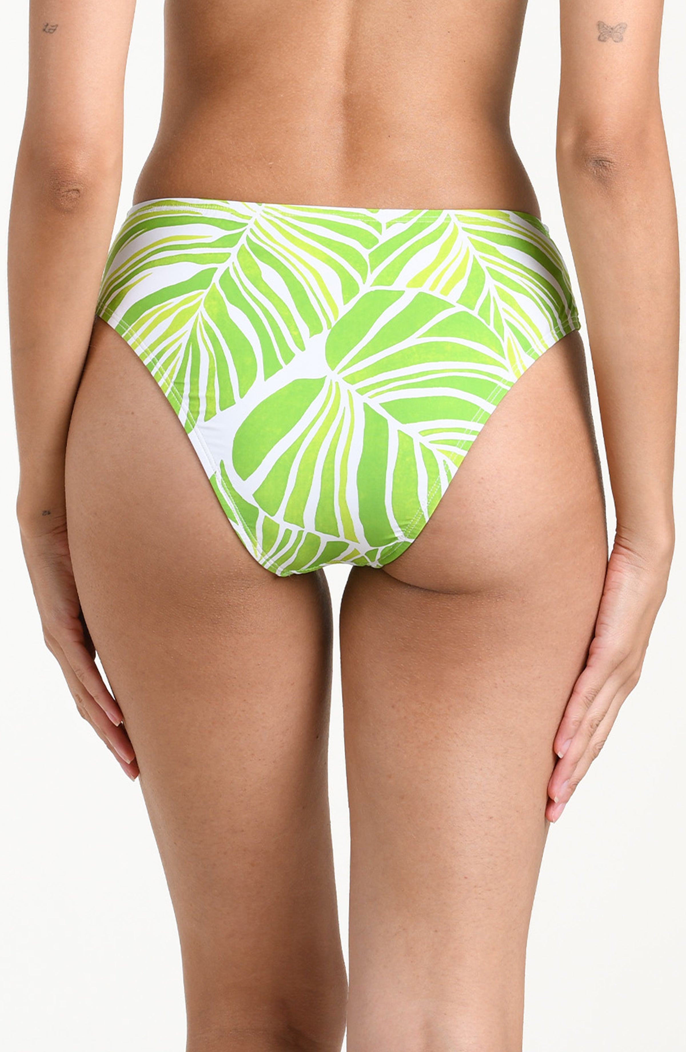 Woman wearing a green and white patterned bikini bottom on a white background