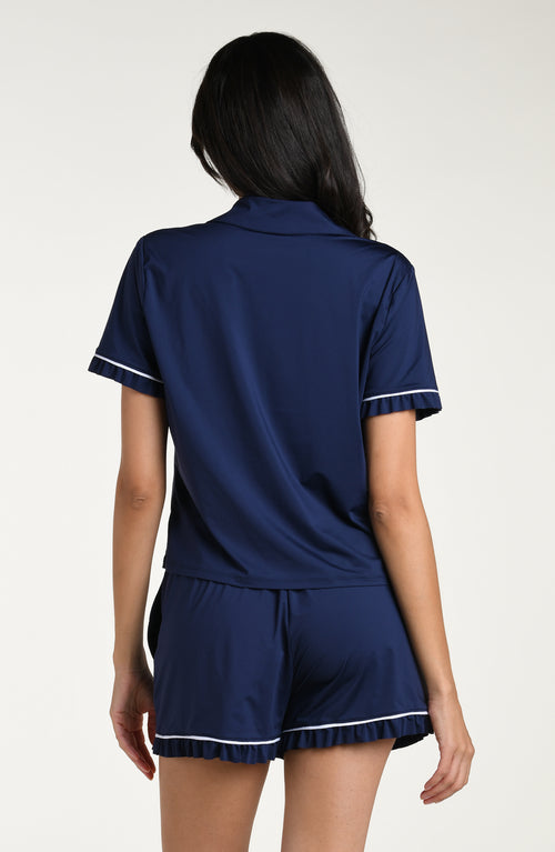 Woman wearing a navy blue pajama set with white trim on a white background
