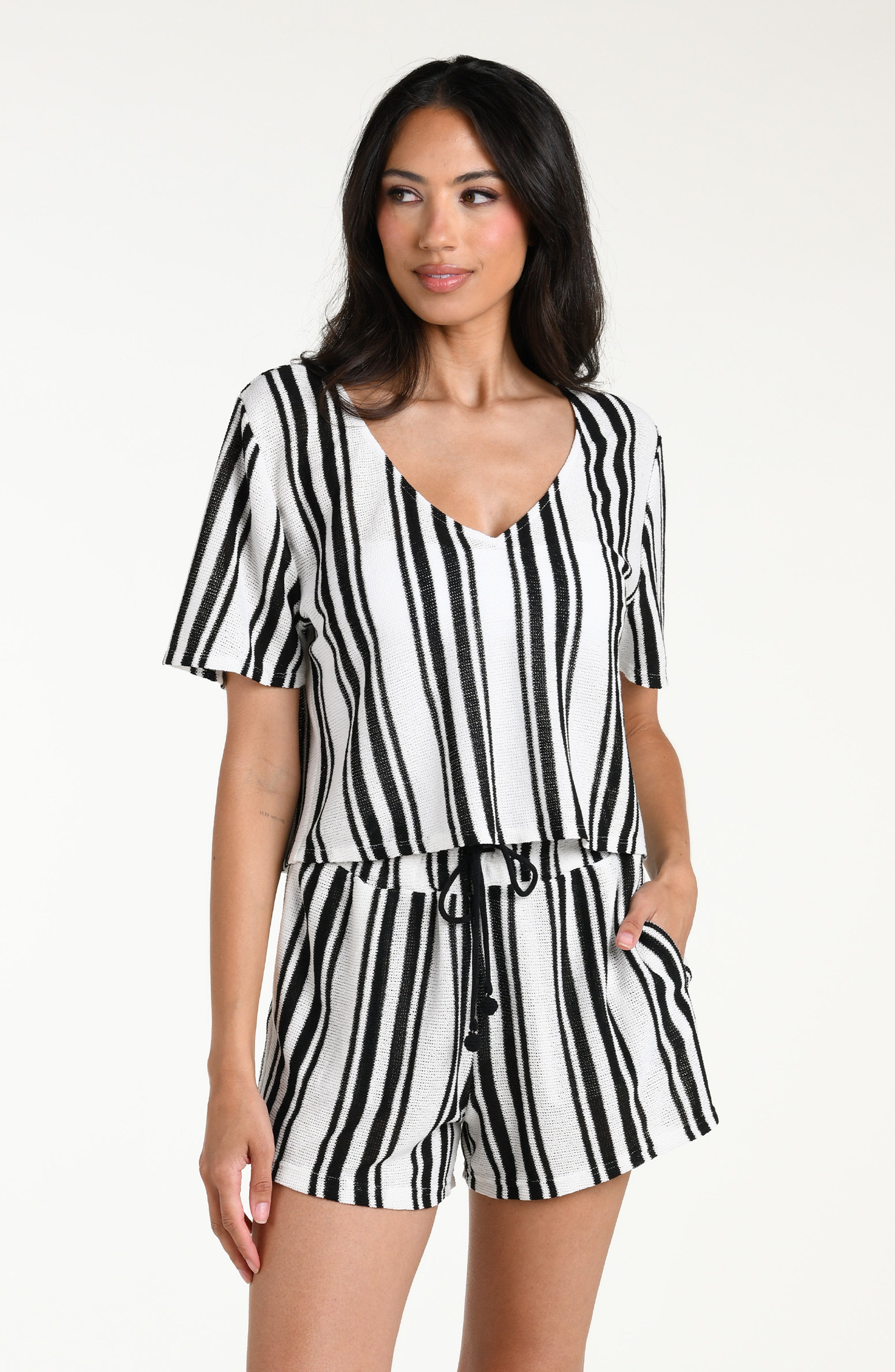 Woman wearing a black and white striped short sleeve top and matching shorts against a white background