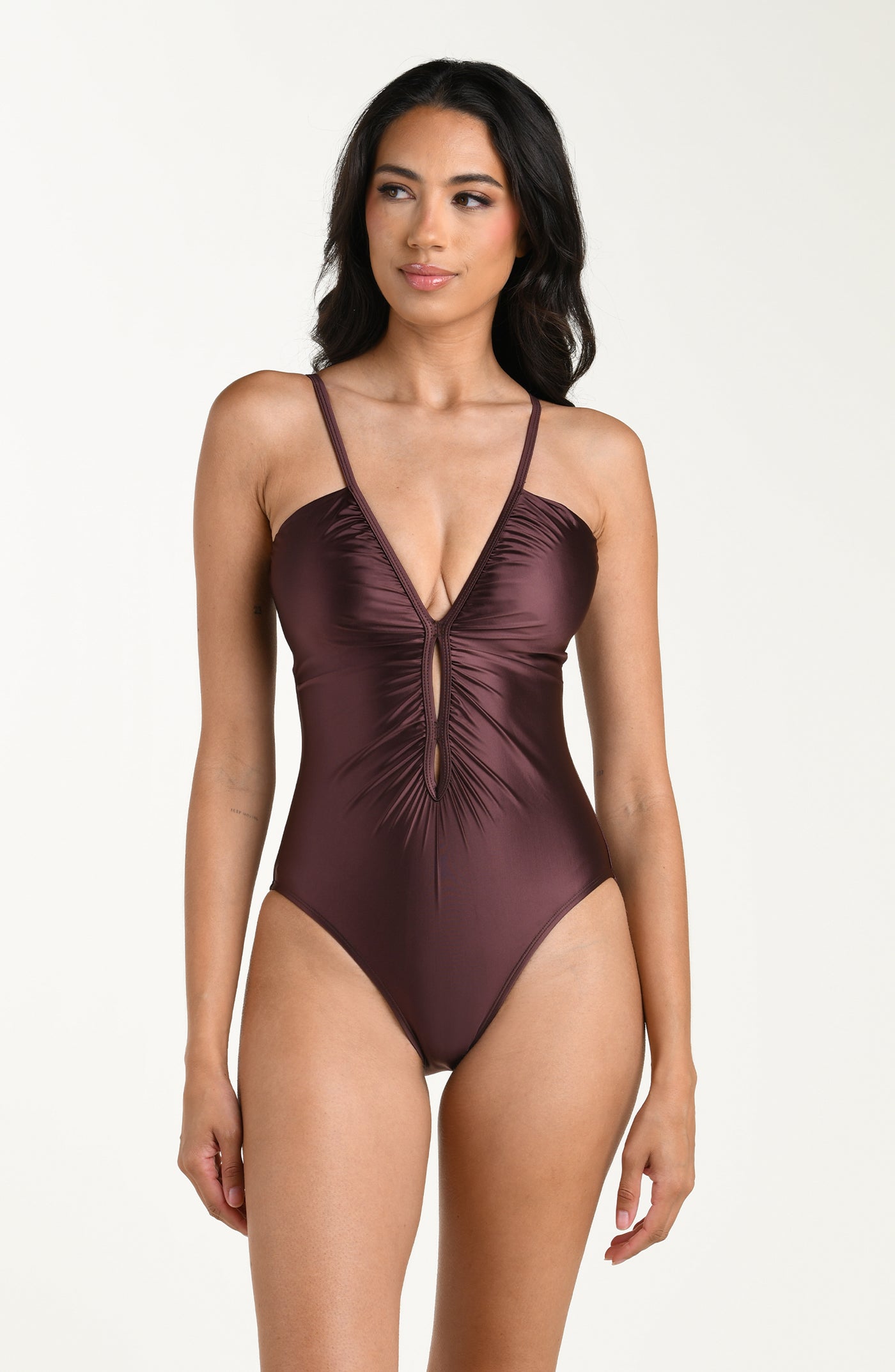 
                  
                    Front image of model wearing a one-piece swimsuit in a truffle (brown) color with thin over the shoulder straps, a plunging V-neckline, and ruched detailing down the front.
                  
                