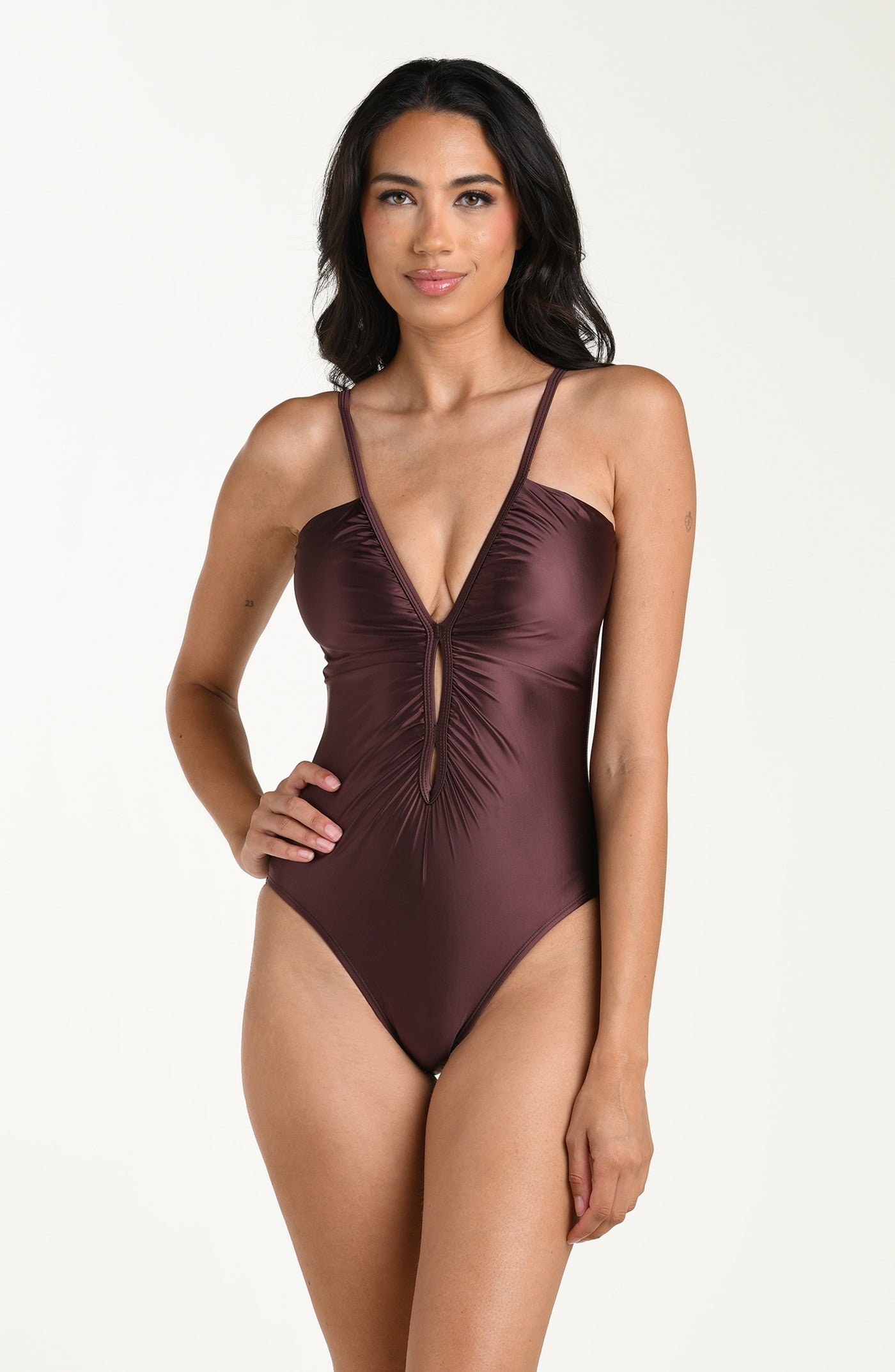 
                  
                    Front image of model wearing a one-piece swimsuit in a truffle (brown) color with thin over the shoulder straps, a plunging V-neckline, and ruched detailing down the front.
                  
                