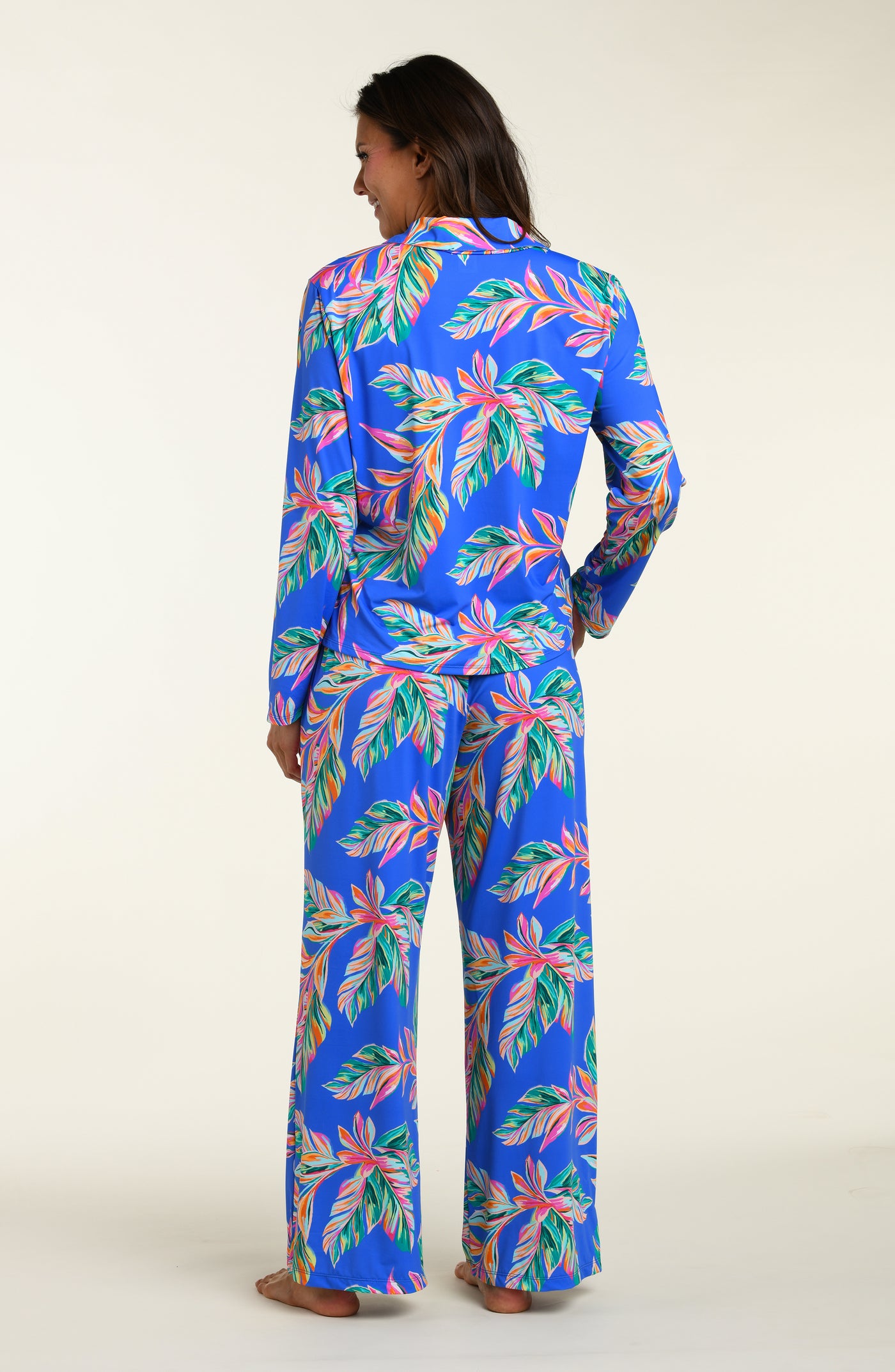 
                  
                    Person wearing a colorful tropical print pajama set on a white background
                  
                
