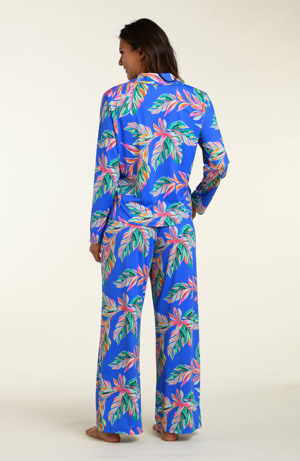 Person wearing a colorful tropical print pajama set on a white background