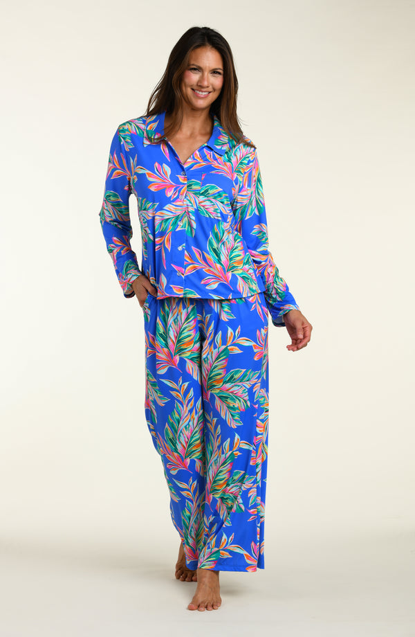 Woman wearing a colorful tropical leaf pattern pajama set on a white background