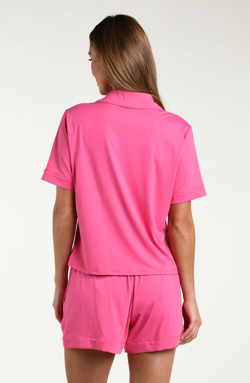 Woman wearing a pink pajama set on a white background.
